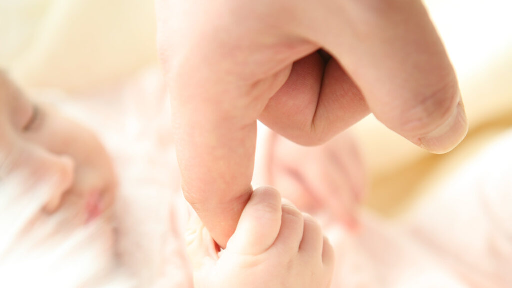 ママの指を握る生まれたての赤ちゃん